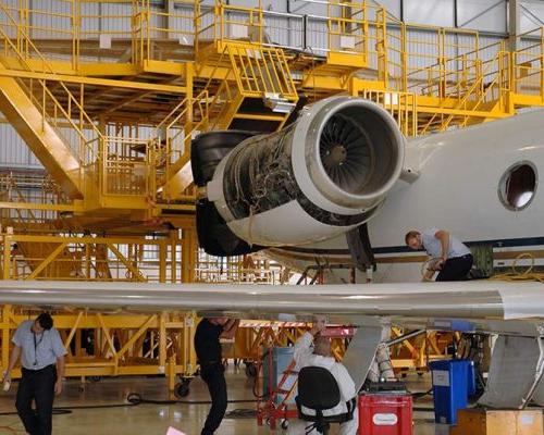 Men working on airplane inside the Gulfstream International Service Facility.