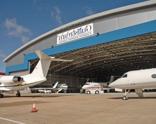 Exterior of Gulfstream International Service Facility with planes within the hangar.